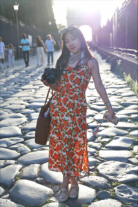 Xin Liu standing in front of the Arch of Constantine, where she is backlit by the sun.